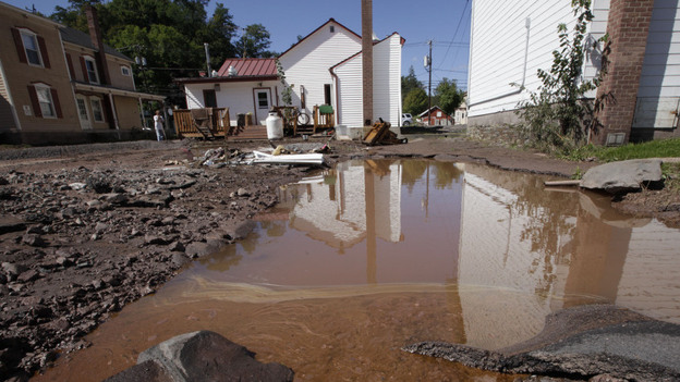 Water mixed with gasoline accumulated in the Zerega's pizzeria parking lot last month in Windham, N.Y. More than a dozen towns in Vermont and at least three in New York were cut off, with roads and bridges washed out by flooding caused by Tropical Storm Irene.